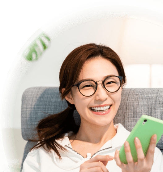 スマホを手に持ち笑顔の女性の画像